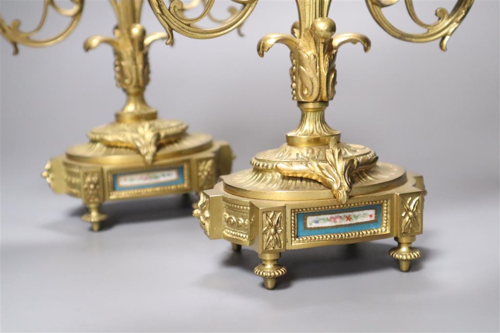 An early 20th century pair of ormolu and porcelain candelabra, with Sevres style plaques to base, height 28cm